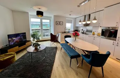a kitchen and living room with a table and chairs at Penthouse Mill park train station in Cambridge