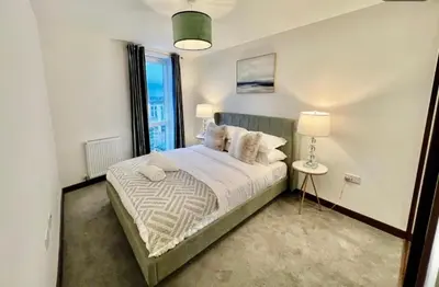 a bedroom with a bed with a lamp and a window at Penthouse Mill park train station in Cambridge