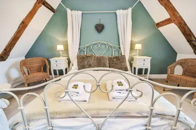 a bedroom with a white bed with two chairs at 3 Bed in Blythburgh oc-h32647 in Blyford