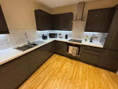 a kitchen with black cabinets and a wooden floor at Apartment in Suffolk in Ipswich