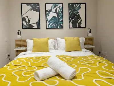 a bedroom with a large bed with a yellow and white blanket at Central Bury Apartment with Private Entrance in Bury Saint Edmunds