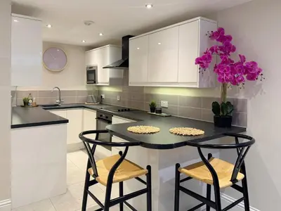 a kitchen with white cabinets and a table with two chairs at Central Bury Apartment with Private Entrance in Bury Saint Edmunds