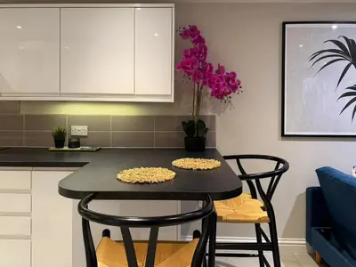 a kitchen with a table with chairs and purple flowers at Central Bury Apartment with Private Entrance in Bury Saint Edmunds