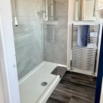 a bathroom with a shower with a glass door at Lime Tree in blue House in Cambridge