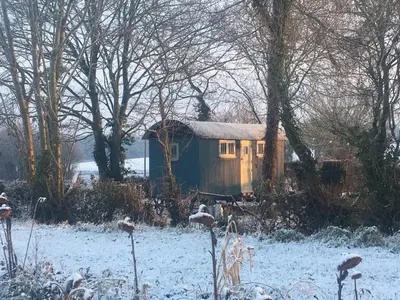a small shed with a snow covered roof in a field at The Scrumpy Shepherd, Brandeston in Blundeston
