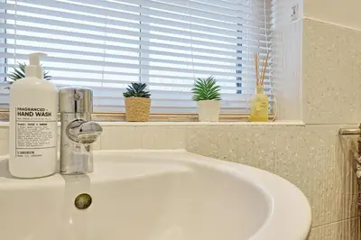 a bathroom sink with a bottle of soap and a window at Spacious 4BR Townhouse, Sleeps 9, Fast WIFI, FREE PARKING, Contractor friendly in Colchester