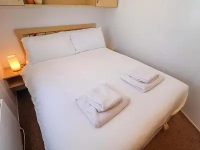 a bedroom with a white bed with towels on it at 21 Poplar Avenue in Felixstowe