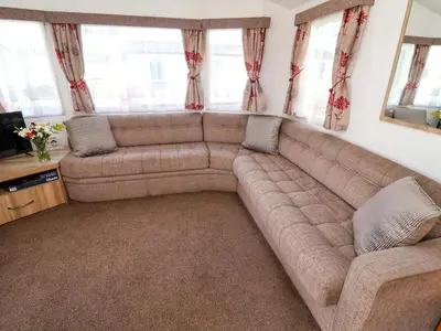 a large couch in a living room with windows at 21 Poplar Avenue in Felixstowe