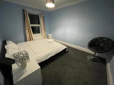 a bedroom with a bed and a chair and a window at Gilead Grace House in Littleport