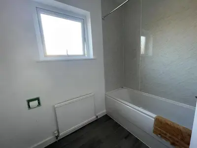 a white bathroom with a tub and a window at Gilead Grace House in Littleport