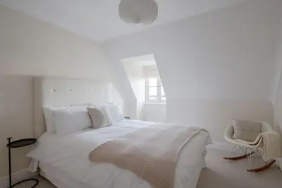 a white bedroom with a bed and a chair at Amazing Abodes in Chelmsford