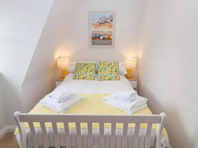 a small bedroom with a white bed with two lamps at Old Felixstowe, Bath Road in Felixstowe