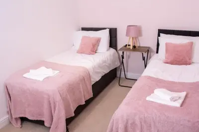 a bedroom with two beds with pink and white sheets at Newly Renovated Sanctuary for 4 in Charlotte House in Ipswich