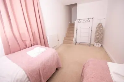a bedroom with a pink bed and a staircase at Newly Renovated Sanctuary for 4 in Charlotte House in Ipswich