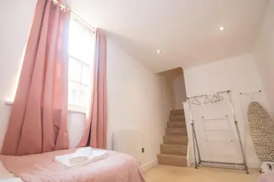 a bedroom with a bed and a window and stairs at Newly Renovated Sanctuary for 4 in Charlotte House in Ipswich