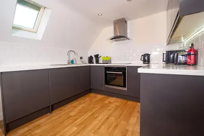 a kitchen with gray cabinets and a wooden floor at Newly Renovated Sanctuary for 4 in Charlotte House in Ipswich