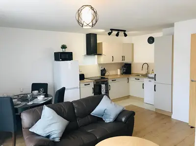 a living room with a couch and a kitchen at Spacious 2-Bed Flat in Homerton House in Cambridge