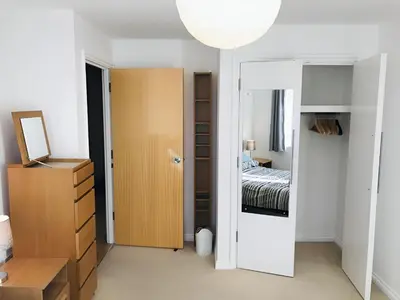 a bedroom with a bed and a closet and a mirror at Spacious 2-Bed Flat in Homerton House in Cambridge
