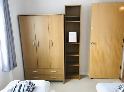 a bedroom with a large wooden cabinet next to a bed at Spacious 2-Bed Flat in Homerton House in Cambridge