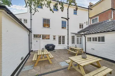 a patio with two picnic tables in front of a building at 6 Angel Hill, Bury st Edmunds in Bury Saint Edmunds