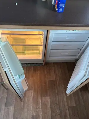 an open refrigerator in a kitchen with wooden floors at 2 Bedroom caravan in Saint Osyth