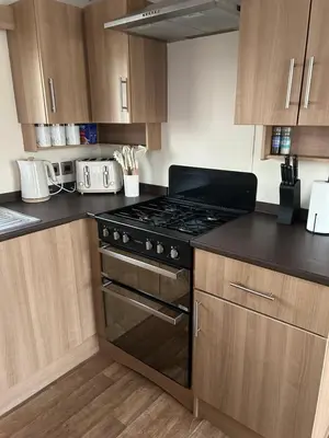 a kitchen with a stove and wooden cabinets at 2 Bedroom caravan in Saint Osyth