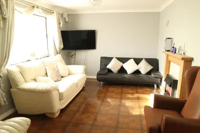 a living room with a white couch and a black chair at Galleywood House in Great Baddow