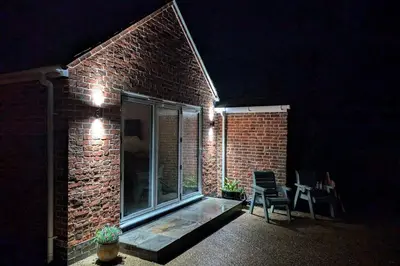a brick building with a window and a table and chairs at Grapnells Lodge, Wallasea Island, Rochford, Essex in Rochford