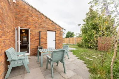 a patio with two benches and a table and chairs at Grapnells Lodge, Wallasea Island, Rochford, Essex in Rochford