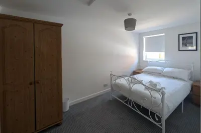 a bedroom with a bed and a wooden cabinet at Grapnells Lodge, Wallasea Island, Rochford, Essex in Rochford