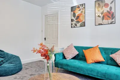 a living room with a green couch and a table at 3 Bedroom Property, Free Parking for 3 Vehicles in Mile End