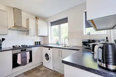 a kitchen with white cabinets and a washer and dryer at 3 Bedroom Property, Free Parking for 3 Vehicles in Mile End