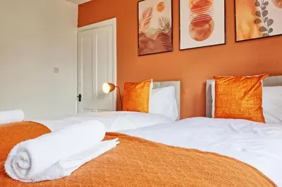 two beds in a room with orange walls at 3 Bedroom Property, Free Parking for 3 Vehicles in Mile End