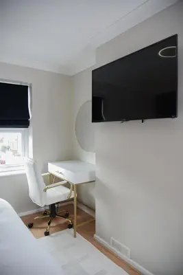 a bedroom with a desk and a tv on a wall at Cosy Luxe 3Bed Retreat Hot Tub BBQ Parking Near Town Perfect for Contractors Families Short & Long Stay in Hythe