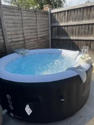 a hot tub in a backyard with a glass of wine at Cosy Luxe 3Bed Retreat Hot Tub BBQ Parking Near Town Perfect for Contractors Families Short & Long Stay in Hythe