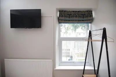 a room with a window with a flat screen tv at Cosy Luxe 3Bed Retreat Hot Tub BBQ Parking Near Town Perfect for Contractors Families Short & Long Stay in Hythe