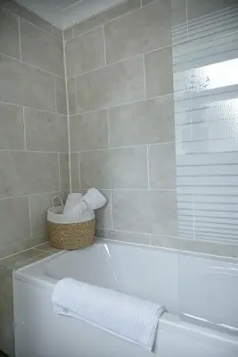 a bathroom with a bath tub with a basket of towels at Cosy Luxe 3Bed Retreat Hot Tub BBQ Parking Near Town Perfect for Contractors Families Short & Long Stay in Hythe