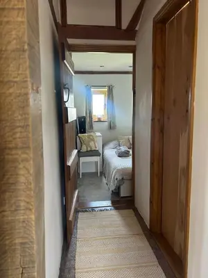 a hallway with a bedroom with a bed and a window at Heritage Cottage with a Pool in Diss