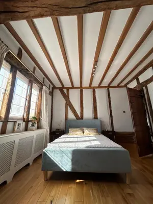 a bedroom with a bed in a room with wooden ceilings at Heritage Cottage with a Pool in Diss