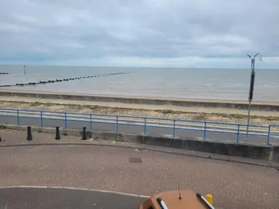 a view of the ocean and a beach with a windmill at Seaview house - Three bedroom house with close access to beach by Catchpole Stays in Clacton-on-Sea