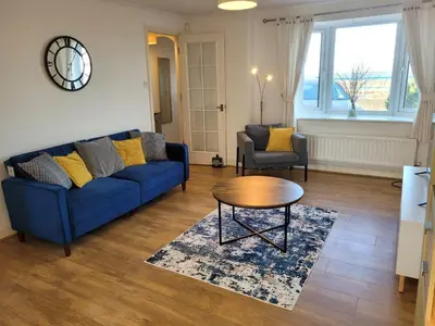a living room with a blue couch and a table at Seaview house - Three bedroom house with close access to beach by Catchpole Stays in Clacton-on-Sea