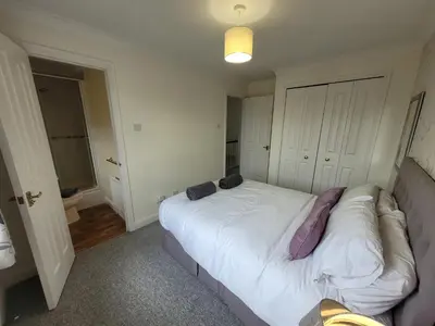 a bedroom with a large white bed with purple pillows at Seaview house - Three bedroom house with close access to beach by Catchpole Stays in Clacton-on-Sea