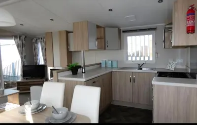a kitchen with white cabinets and a table and chairs at Lovely Caravan At Carlton Meres Holiday Park Ref 60034O in Saxmundham