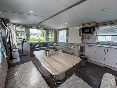 a rv living room with a table and a couch at Cosy 8 Berth Caravan With Decking And Lake-Views At Weeley Bridge Ref 69001Lv in Clacton-on-Sea