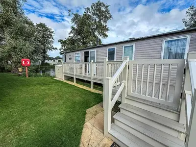 a house with a white fence and a yard at Cosy 8 Berth Caravan With Decking And Lake-Views At Weeley Bridge Ref 69001Lv in Clacton-on-Sea