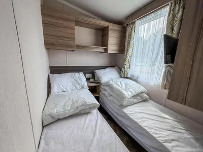 two beds in a small room with a window at Cosy 8 Berth Caravan With Decking And Lake-Views At Weeley Bridge Ref 69001Lv in Clacton-on-Sea