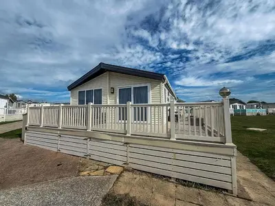 a small house with a white railing on a porch at Stunning Lodge With Full Sea Views At Coopers Beach Holiday Park Ref 49019S in East Mersea