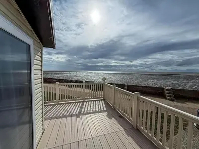 a view of the ocean from a house balcony at Stunning Lodge With Full Sea Views At Coopers Beach Holiday Park Ref 49019S in East Mersea