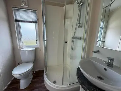 a bathroom with a shower and a toilet and a sink at Stunning Lodge With Full Sea Views At Coopers Beach Holiday Park Ref 49019S in East Mersea