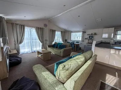a living room with two couches and a kitchen at Stunning Lodge With Full Sea Views At Coopers Beach Holiday Park Ref 49019S in East Mersea
